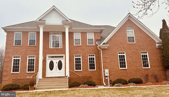 greek revival inspired property with entry steps and brick siding