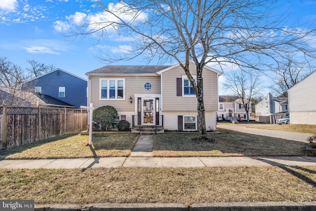 raised ranch with a front yard, fence, and a residential view