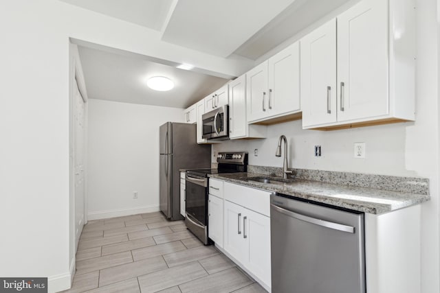 kitchen featuring a sink, white cabinetry, baseboards, appliances with stainless steel finishes, and wood tiled floor