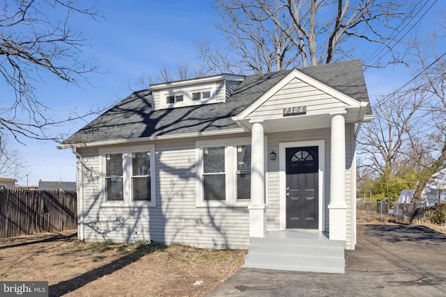 view of front of property featuring a shingled roof and fence