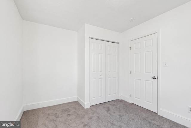 unfurnished bedroom with light carpet, baseboards, and a closet