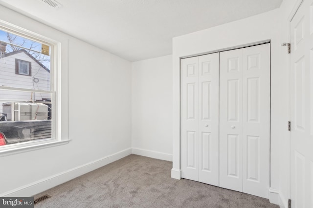 unfurnished bedroom featuring baseboards, a closet, visible vents, and light colored carpet