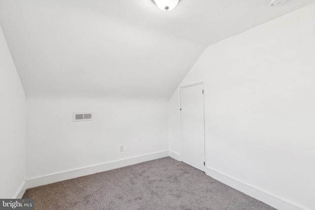 additional living space with lofted ceiling, light carpet, and baseboards