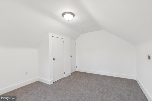 additional living space with lofted ceiling, light carpet, and baseboards