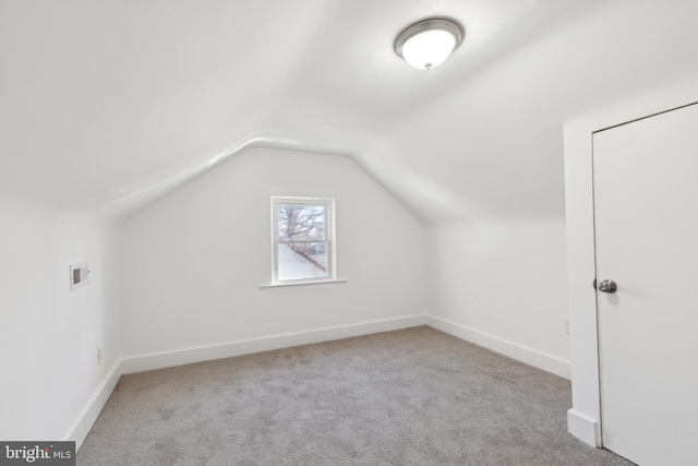 additional living space featuring lofted ceiling, light colored carpet, and baseboards