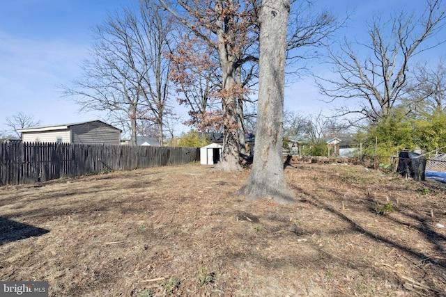 view of yard featuring an outbuilding, fence, and a shed