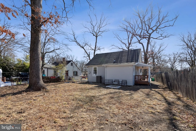 back of house with a shingled roof, cooling unit, and fence