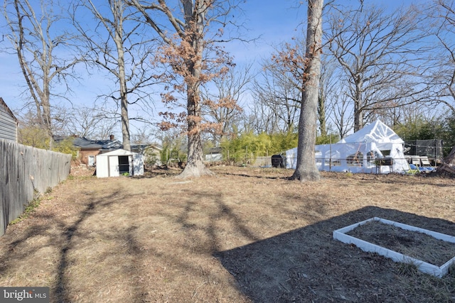 view of yard with fence, an outdoor structure, and a shed