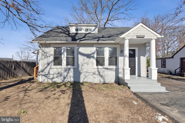 view of front facade featuring roof with shingles and fence