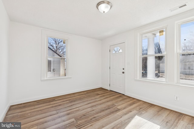 entryway featuring light wood-type flooring, visible vents, a textured ceiling, and baseboards