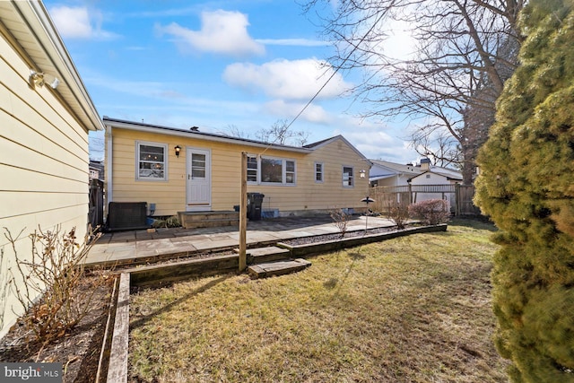 rear view of house with central AC, a patio area, and a lawn