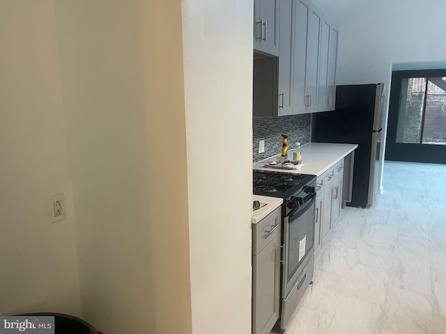 kitchen with gray cabinetry, decorative backsplash, and stainless steel appliances