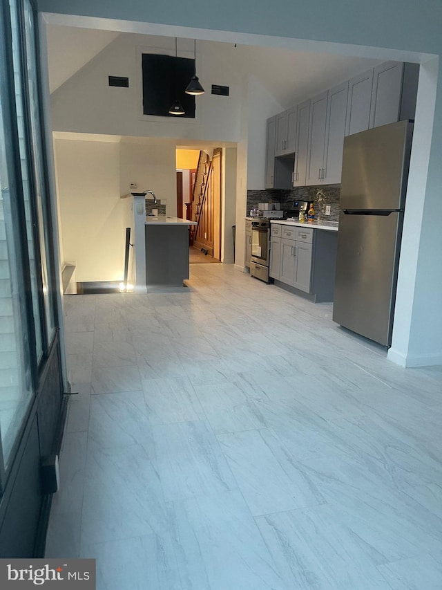 kitchen featuring tasteful backsplash, hanging light fixtures, gray cabinets, and stainless steel appliances