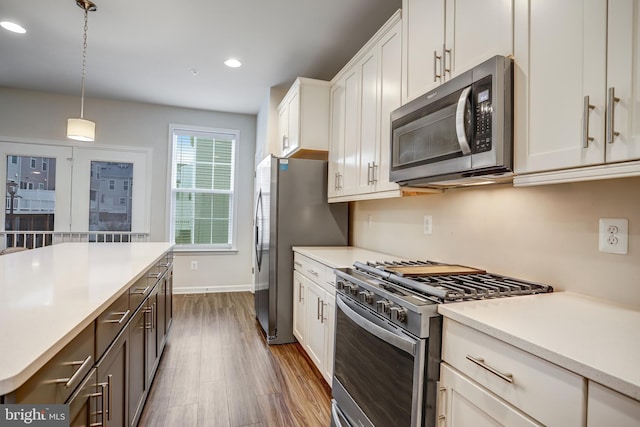 kitchen featuring pendant lighting, white cabinetry, dark wood-type flooring, and appliances with stainless steel finishes