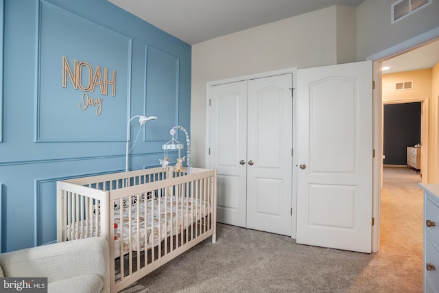 bedroom featuring a crib, carpet, and a closet