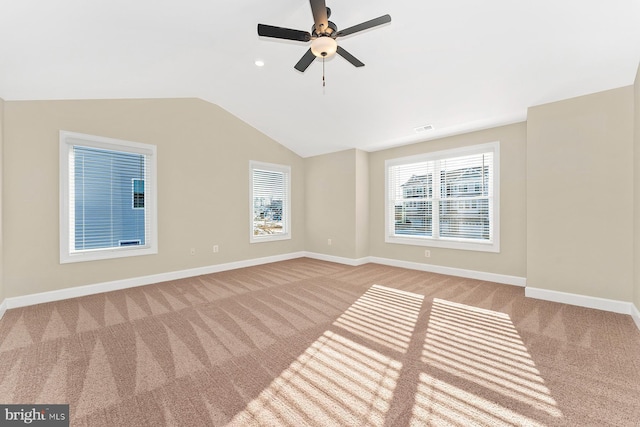 empty room with visible vents, baseboards, a ceiling fan, light colored carpet, and lofted ceiling