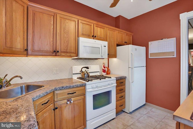 kitchen featuring white appliances, ceiling fan, backsplash, sink, and dark stone countertops