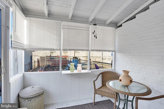 sunroom / solarium featuring vaulted ceiling with beams