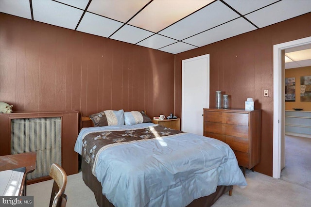 carpeted bedroom with a drop ceiling and wooden walls