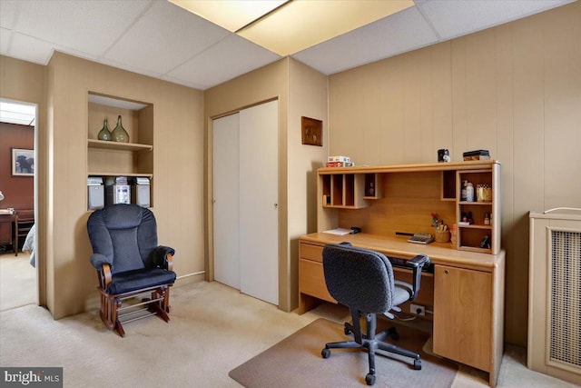 carpeted office space with heating unit, built in features, and a drop ceiling