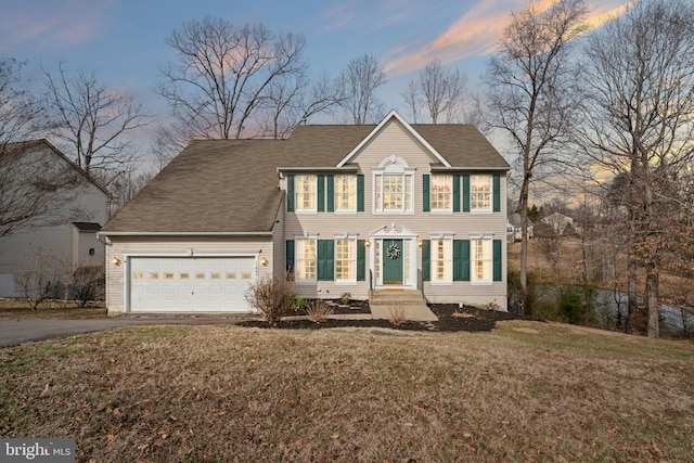 colonial-style house featuring a garage and a lawn