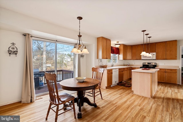 kitchen featuring pendant lighting, white appliances, light hardwood / wood-style flooring, and a center island