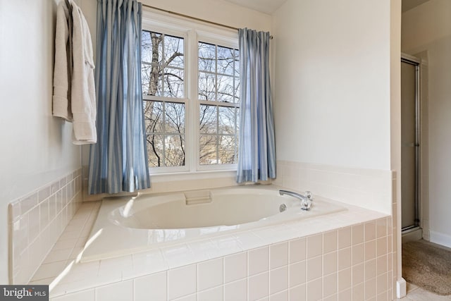 bathroom with a relaxing tiled tub and plenty of natural light