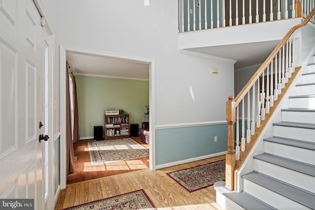 entrance foyer featuring a high ceiling, wood-type flooring, and crown molding