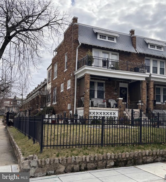 view of front of property featuring a front yard, a balcony, and covered porch