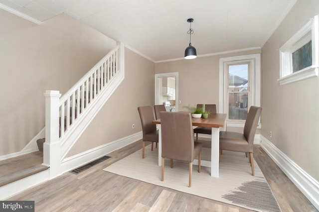 dining area with hardwood / wood-style floors and ornamental molding