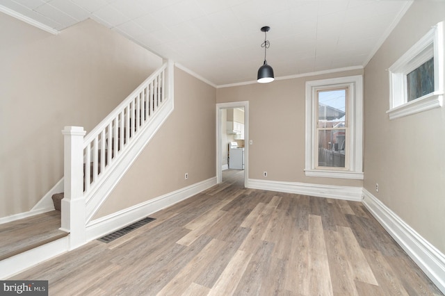 unfurnished dining area with washer / clothes dryer, crown molding, and light wood-type flooring