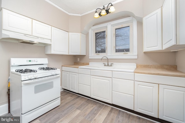 kitchen with sink, light hardwood / wood-style flooring, white gas range oven, and white cabinets