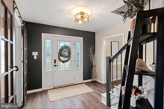 entryway with a barn door, baseboards, wood finished floors, and stairs