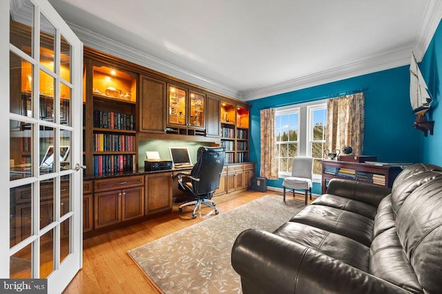 home office featuring ornamental molding, light wood-type flooring, french doors, and built in study area