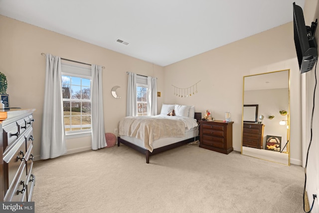 bedroom featuring baseboards, visible vents, and light colored carpet