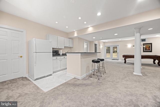 kitchen featuring a breakfast bar, freestanding refrigerator, light carpet, and dark countertops