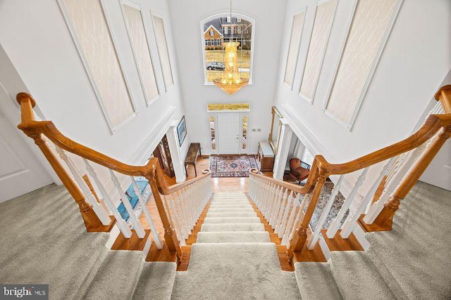 staircase featuring a towering ceiling and a notable chandelier