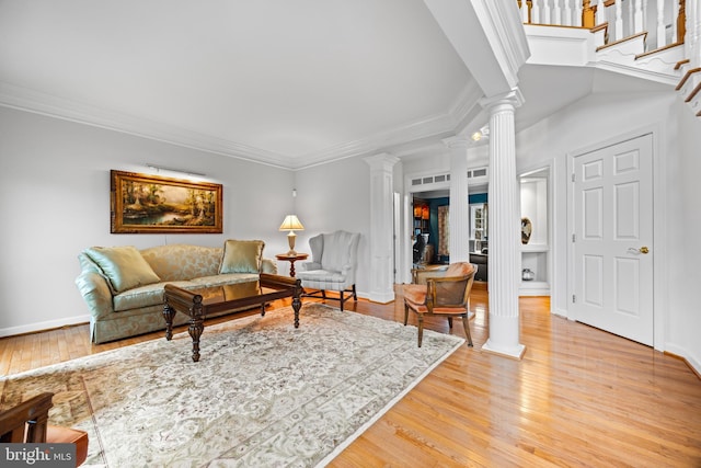 living room with light wood-type flooring, decorative columns, baseboards, and crown molding