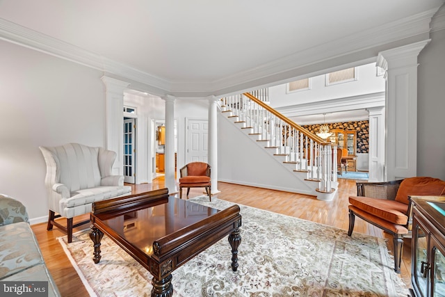 living room with decorative columns, baseboards, stairway, crown molding, and light wood-type flooring