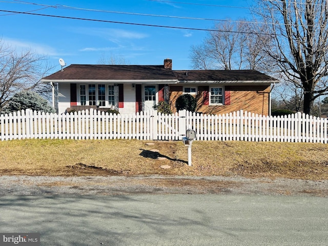 ranch-style home featuring a fenced front yard, a chimney, and brick siding