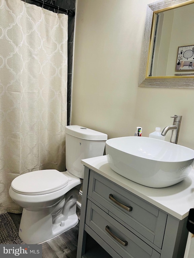 full bathroom with toilet, curtained shower, wood finished floors, and vanity