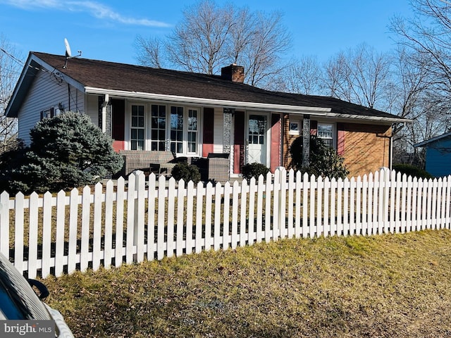 single story home featuring a fenced front yard, brick siding, a chimney, a porch, and a front lawn