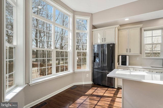 kitchen with black fridge with ice dispenser and light hardwood / wood-style floors