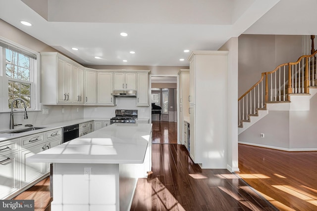 kitchen featuring sink, dark hardwood / wood-style flooring, a center island, stainless steel range, and light stone countertops