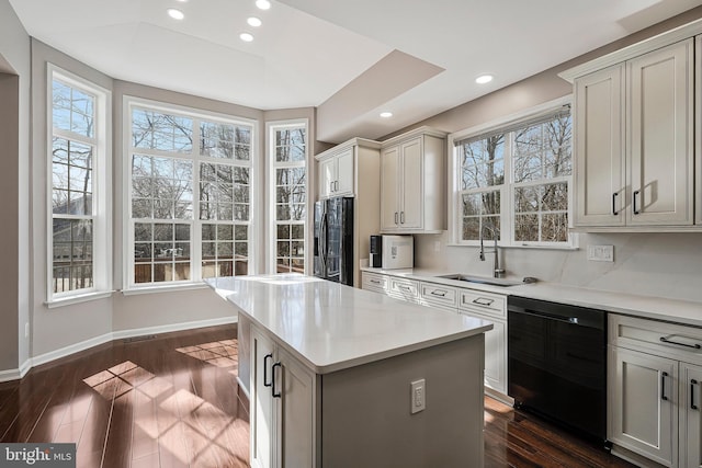 kitchen featuring tasteful backsplash, sink, dark hardwood / wood-style flooring, a center island, and black appliances