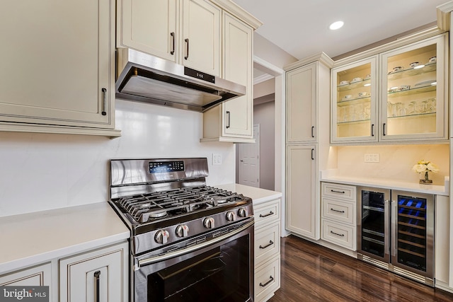 kitchen with dark hardwood / wood-style flooring, cream cabinetry, wine cooler, and stainless steel range with gas stovetop