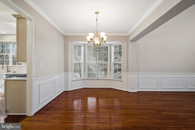 unfurnished dining area featuring an inviting chandelier, dark hardwood / wood-style floors, sink, and crown molding