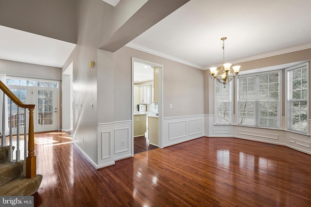 unfurnished dining area with ornamental molding, hardwood / wood-style floors, and a notable chandelier