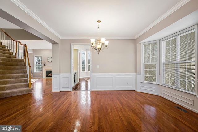 unfurnished dining area with hardwood / wood-style floors, ornamental molding, and a chandelier