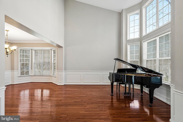 misc room with a notable chandelier, dark wood-type flooring, ornamental molding, and a high ceiling